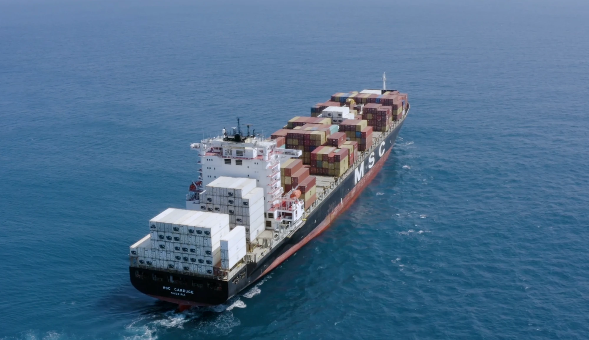 A loaded container ship under way at sea, seen from above